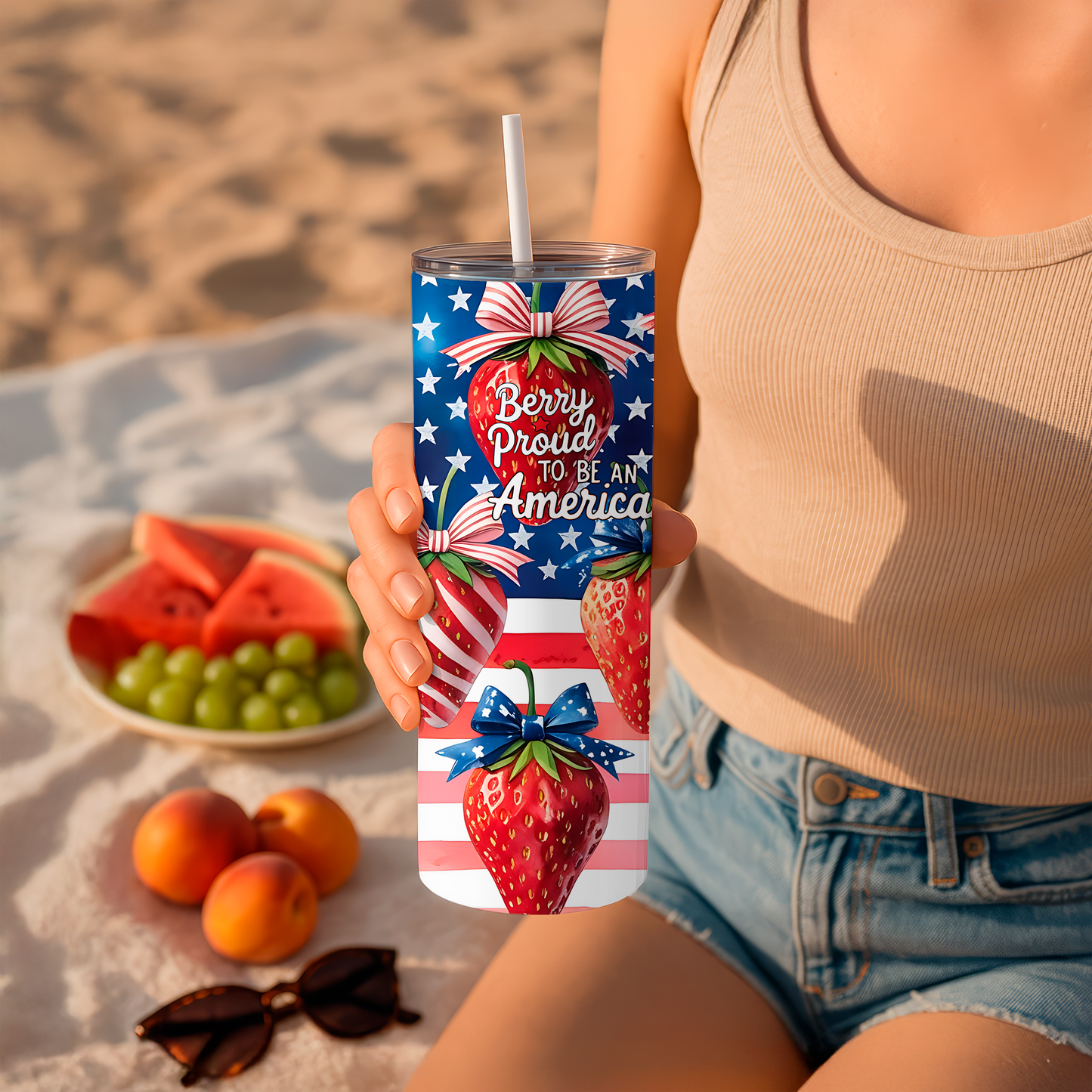 20oz tumbler with patriotic strawberry design and red white blue stars held by person at beach