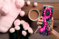 20oz pink tumbler with vibrant floral and leopard print design held over wooden table with coffee and pink knitwear