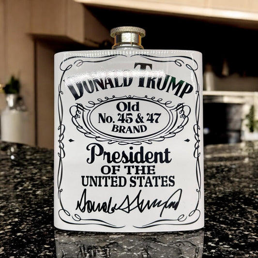 Macies Handmade Treasures white hip flask with Donald Trump design and signature on black granite countertop