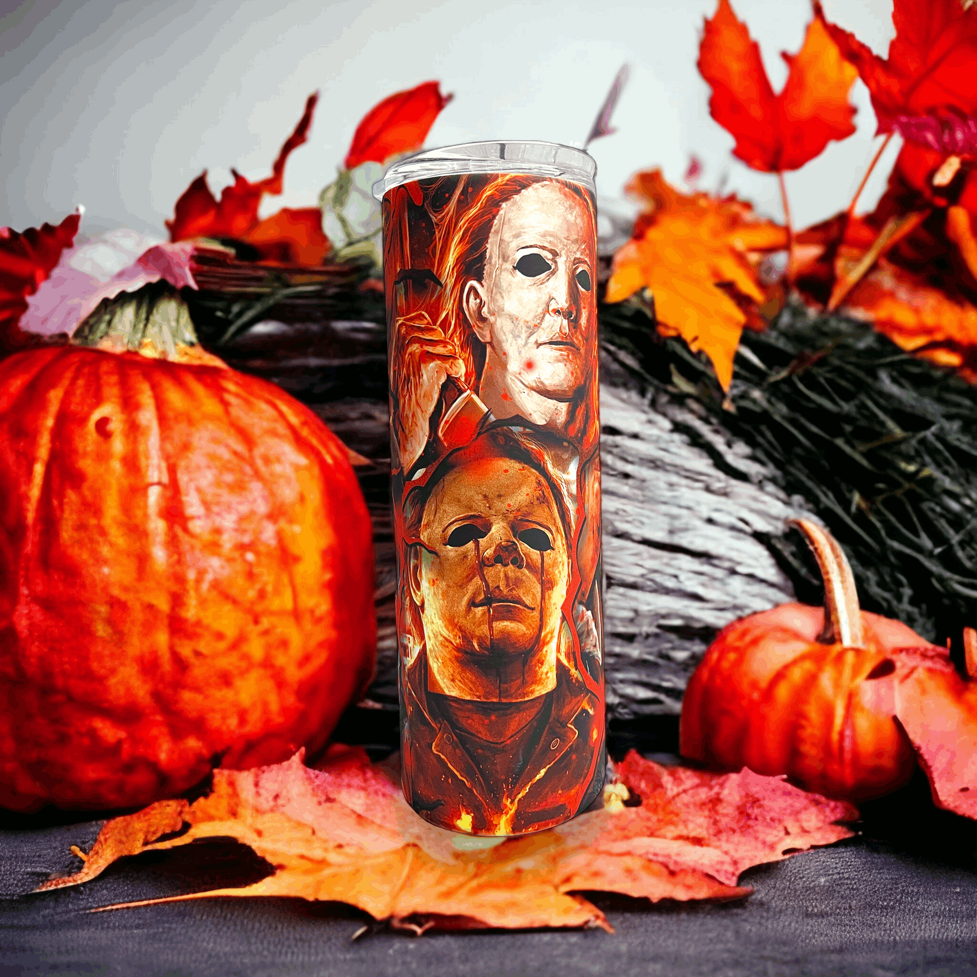 20oz tumbler featuring michael myers in halloween design with fiery background surrounded by pumpkins and autumn leaves